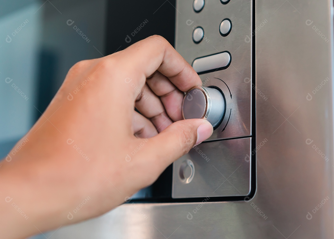 Mão segurando o botão giratório do forno elétrico