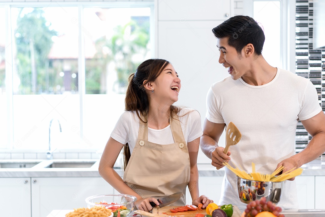 Casal cozinhando comida na cozinha fazendo jantar