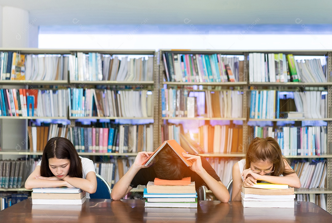 Equipe de estudantes seriamente com seu exame e lendo livro na biblioteca