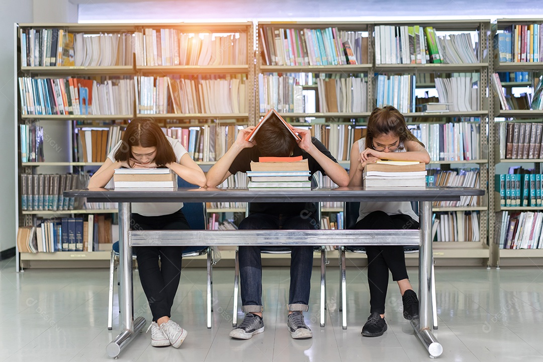 Equipe de estudantes seriamente com seu exame e lendo livro na biblioteca