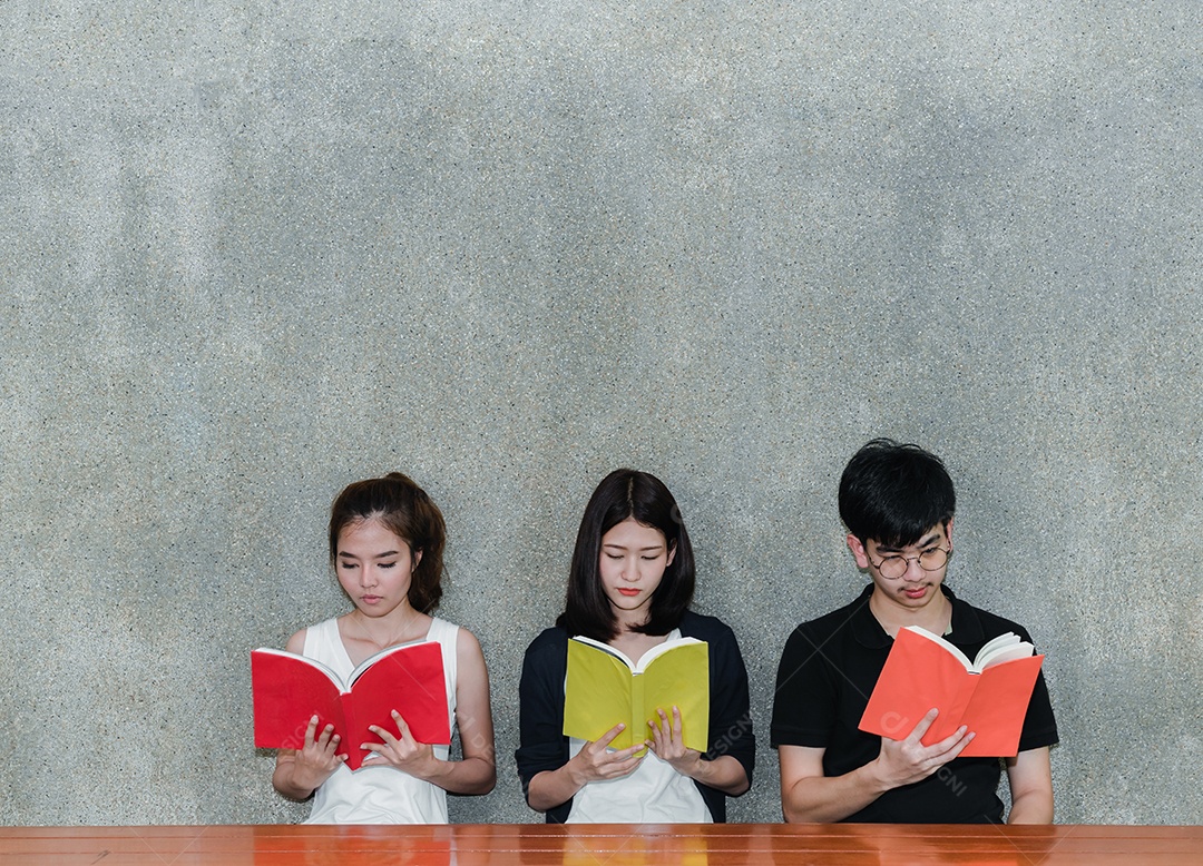 Alunos jovens estudam juntos lendo livro na universidade