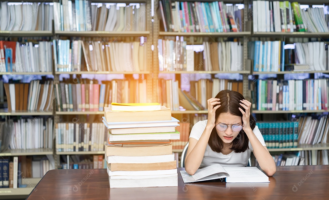 Jovem asiática com óculos seriamente e lendo livro na biblioteca