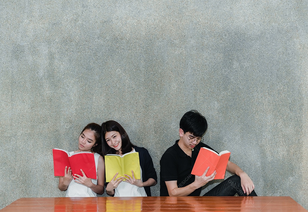 Grupo de jovens estudantes sorrindo lendo livro