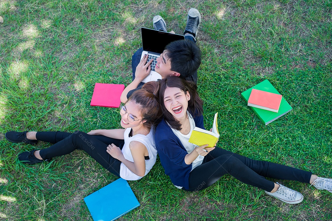 Grupo de jovens estudantes sorrindo com pastas Livro e computador portátil