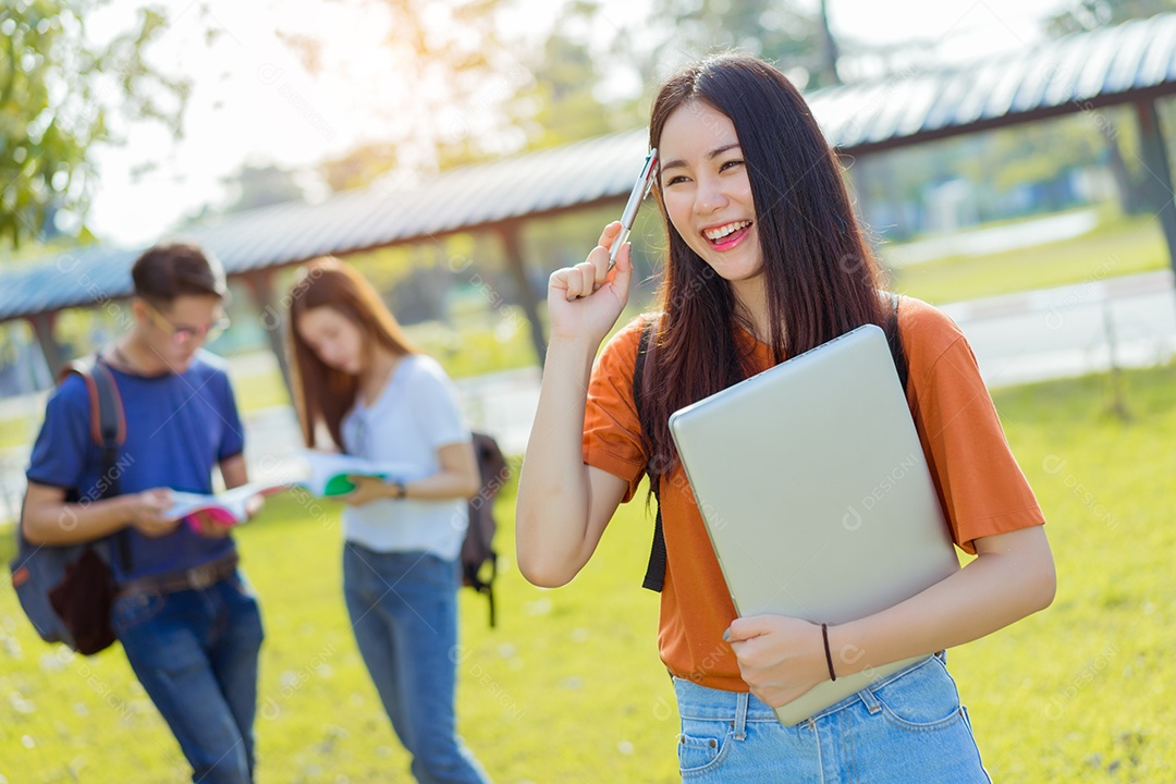 Estudantes asiáticos juntos sorrindo estudo de livro de leitura em grupo com laptop no campus da escola