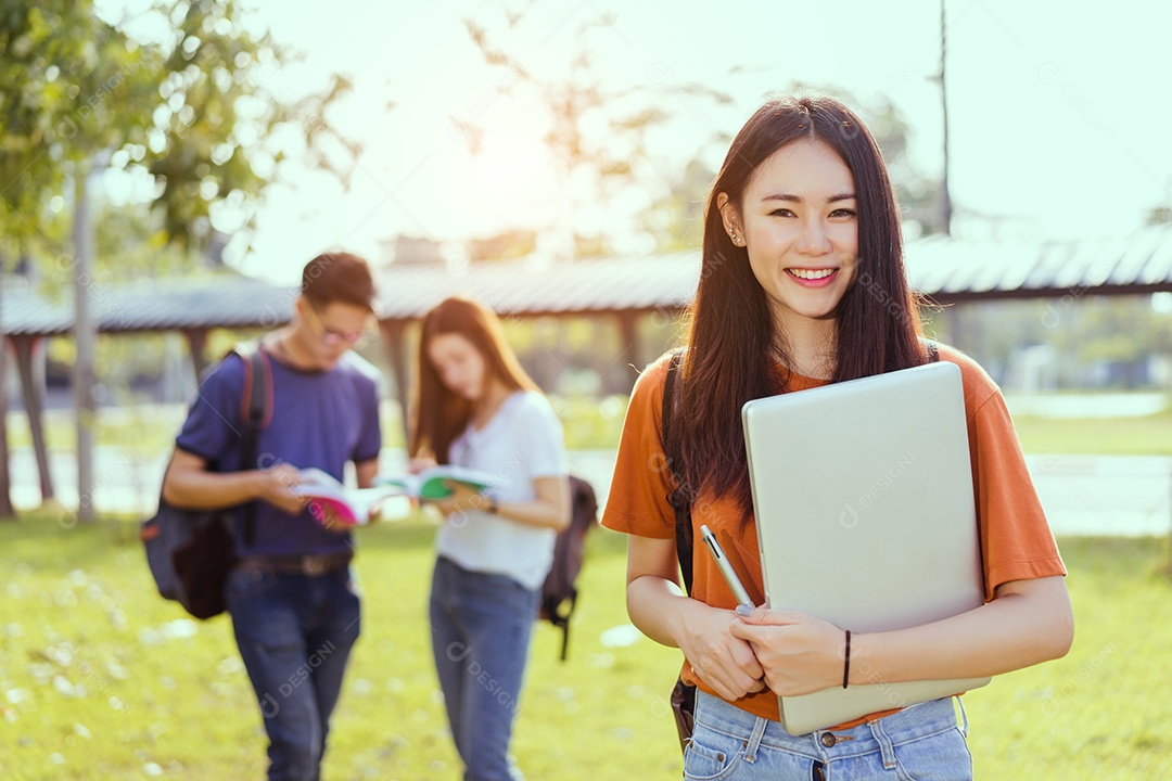 Estudantes asiáticos juntos sorrindo estudo de livro de leitura em grupo com laptop no campus da escola