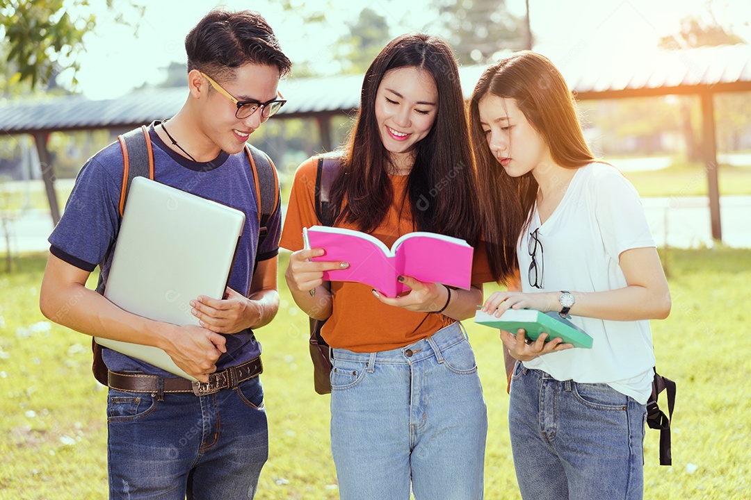 Estudantes asiáticos juntos sorrindo estudo de livro de leitura em grupo com laptop no campus da escola