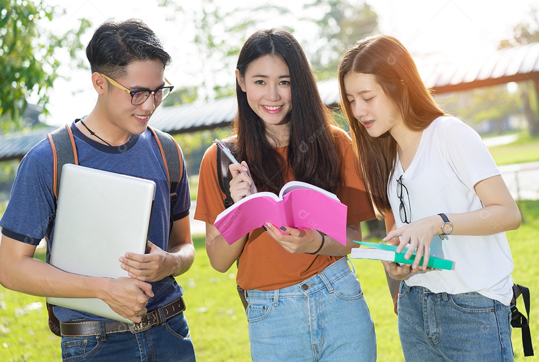 Estudantes asiáticos juntos sorrindo estudo de livro de leitura em grupo com laptop no campus da escola