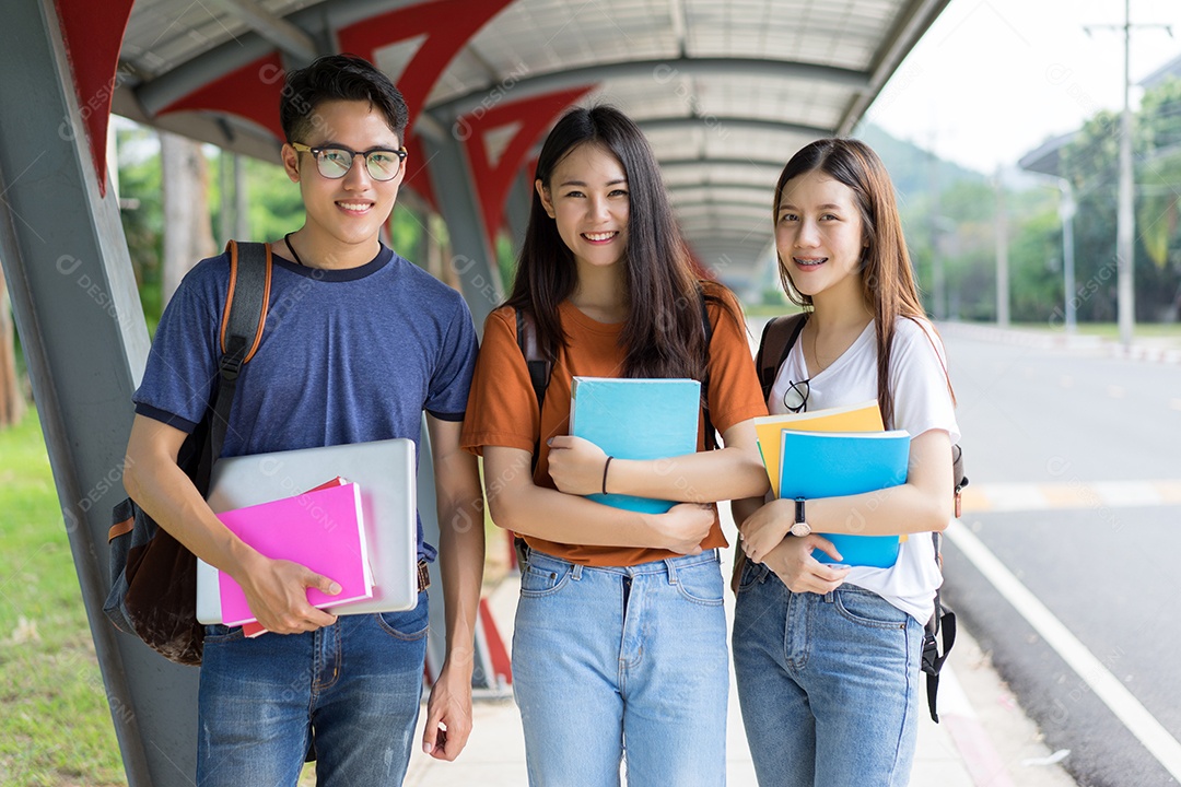 Estudantes asiáticos juntos sorrindo com livros