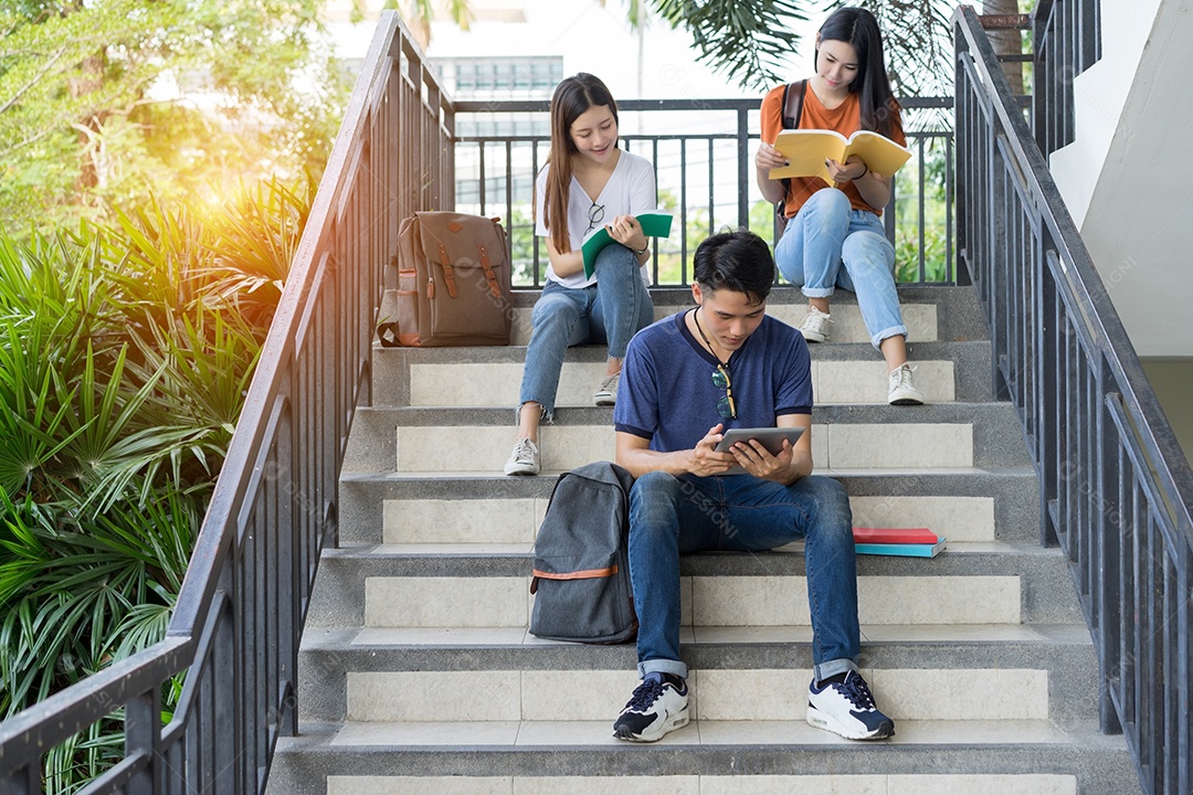 Estudantes jovens asiáticos juntos lendo estudo de livro