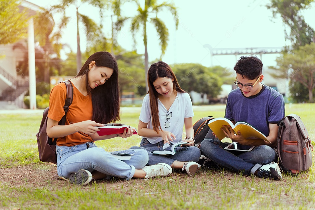 Estudantes jovens asiáticos juntos lendo estudo de livro