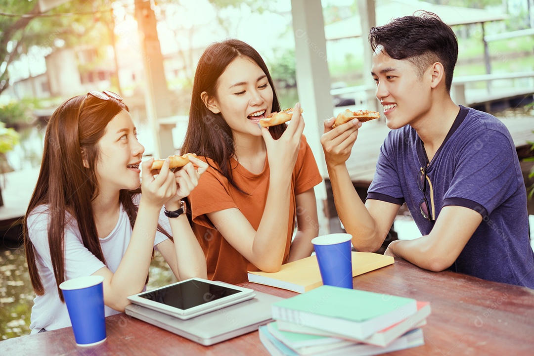 Alunos asiáticos agrupam-se comendo pizza no intervalo