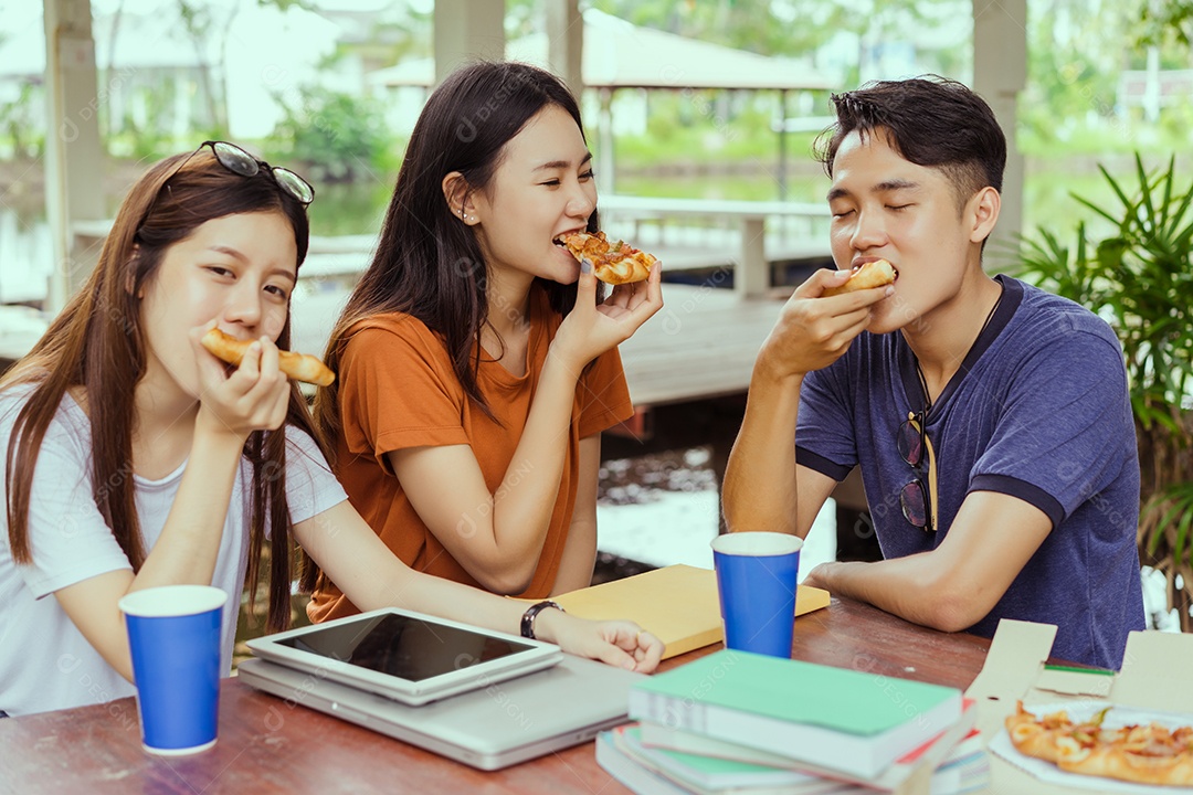 Alunos asiáticos agrupam-se comendo pizza no intervalo