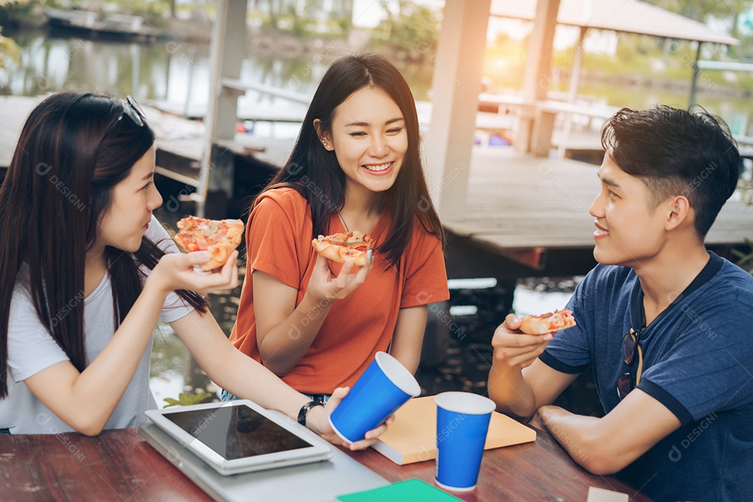 Grupo de jovens asiáticos juntos comendo pizza no intervalo se divertindo
