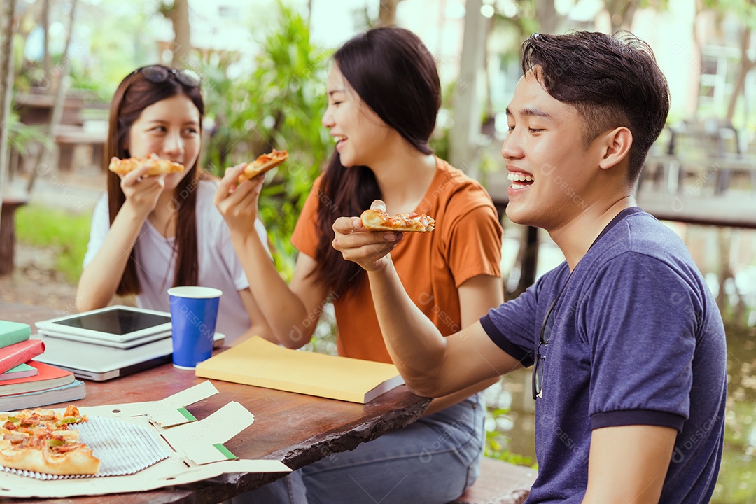 Grupo de jovens asiáticos juntos comendo pizza no intervalo se divertindo