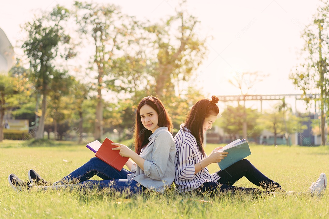 Mulheres jovens juntas estudam lendo livro na universidade