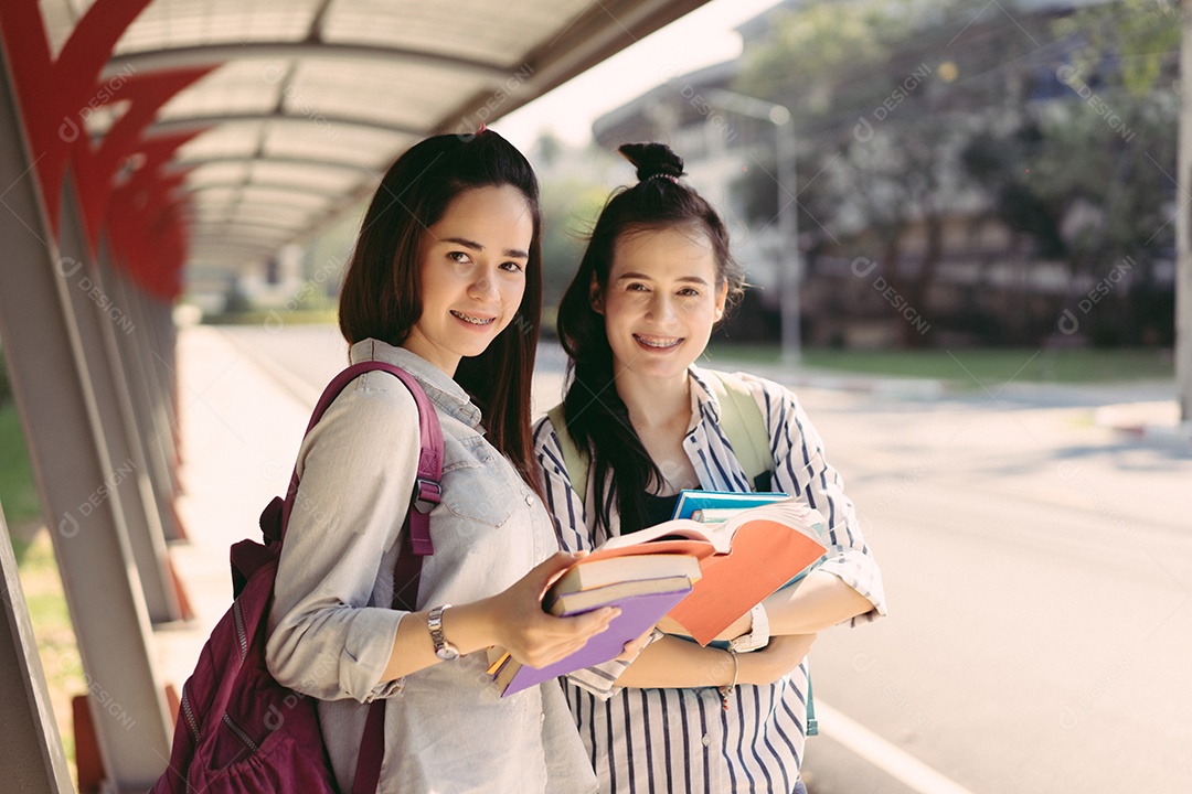 Mulheres jovens juntas estudam lendo livro na universidade