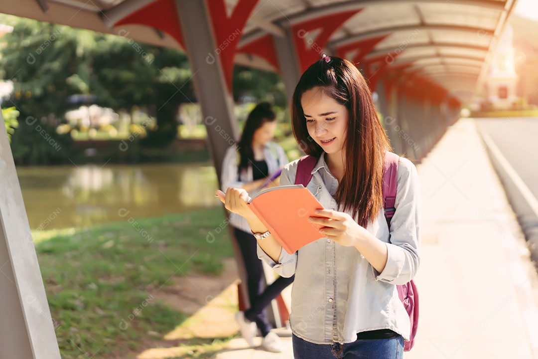 Alunos jovens estudam juntos lendo livro na universidade