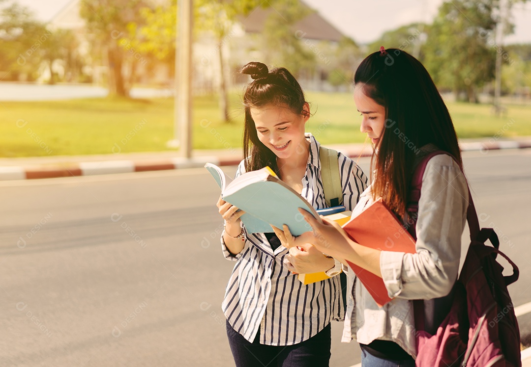 Alunos jovens estudam juntos lendo livro na universidade