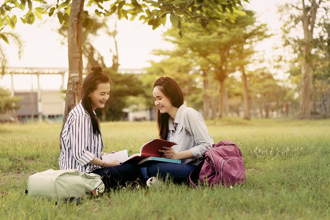 Mulheres jovens juntas estudam lendo livro na universidade