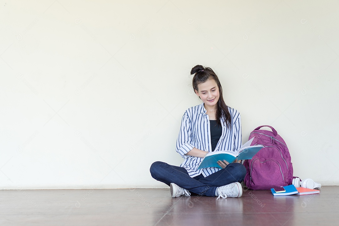 Mulher lendo livros, aprendendo no campus da universidade sentado em ambientes fechados