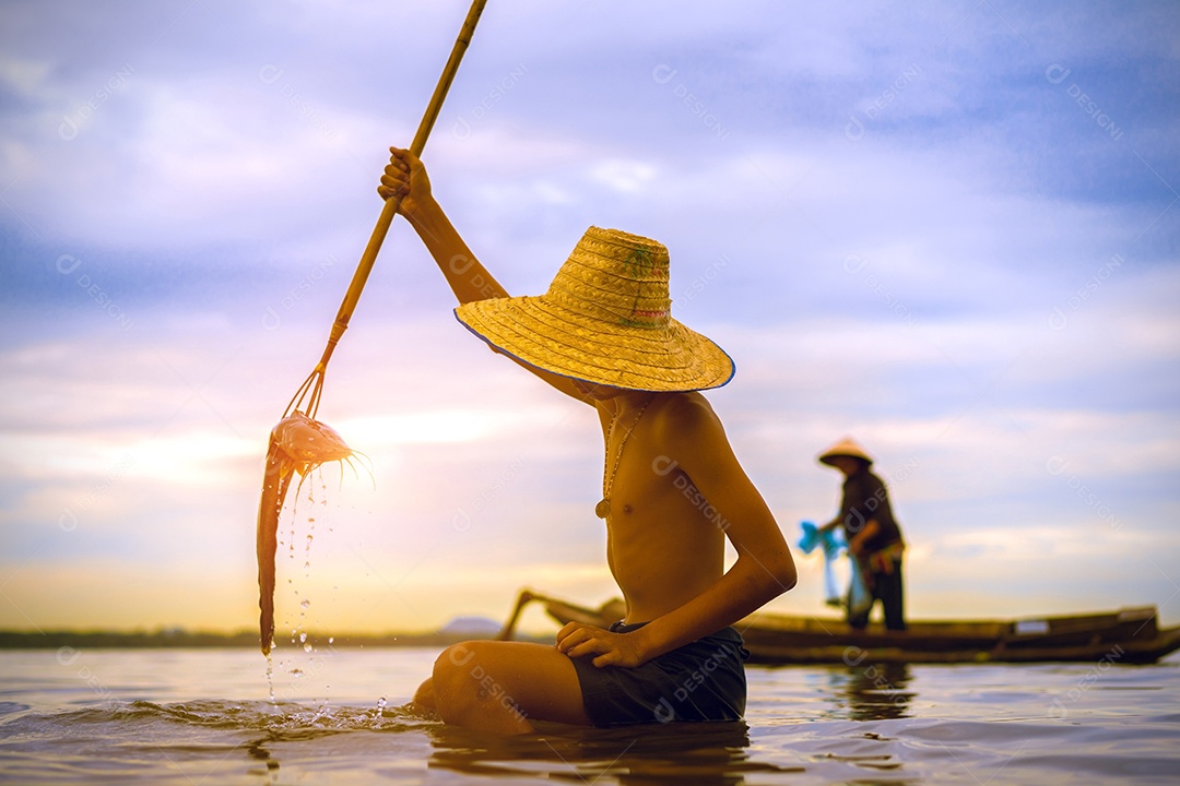 Menino pescador com captura de peixes e pescador jogando redes do barco no lago rio Tailândia