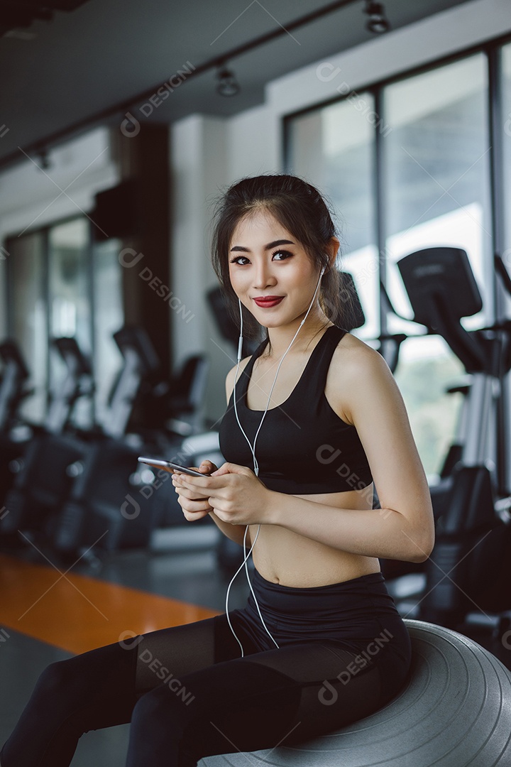 Jovem atleta asiática ouvindo música com smartphone relaxa após o treino