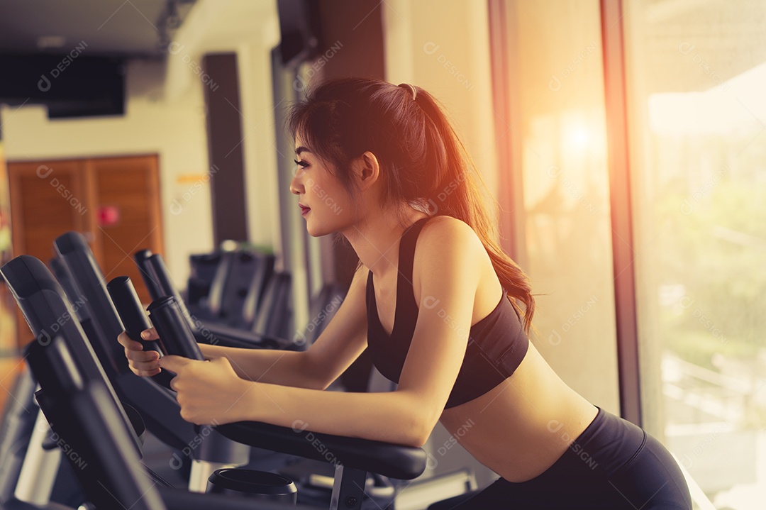 Treino da mulher na bicicleta ergométrica na academia fitness