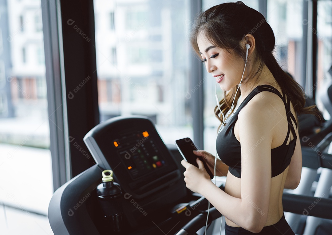 Treino da mulher na esteira de corrida na academia com fones de ouvido