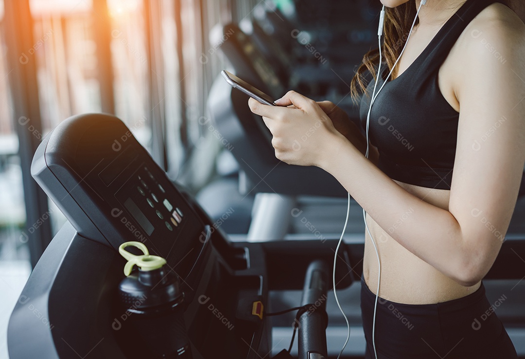 Jovem mulher asiática exercita o treino ouvindo música usando fones de ouvido