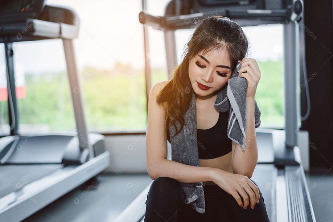 Atleta jovem asiática com lenço relaxa após o treino de intervalo e exercícios cardio esportivos