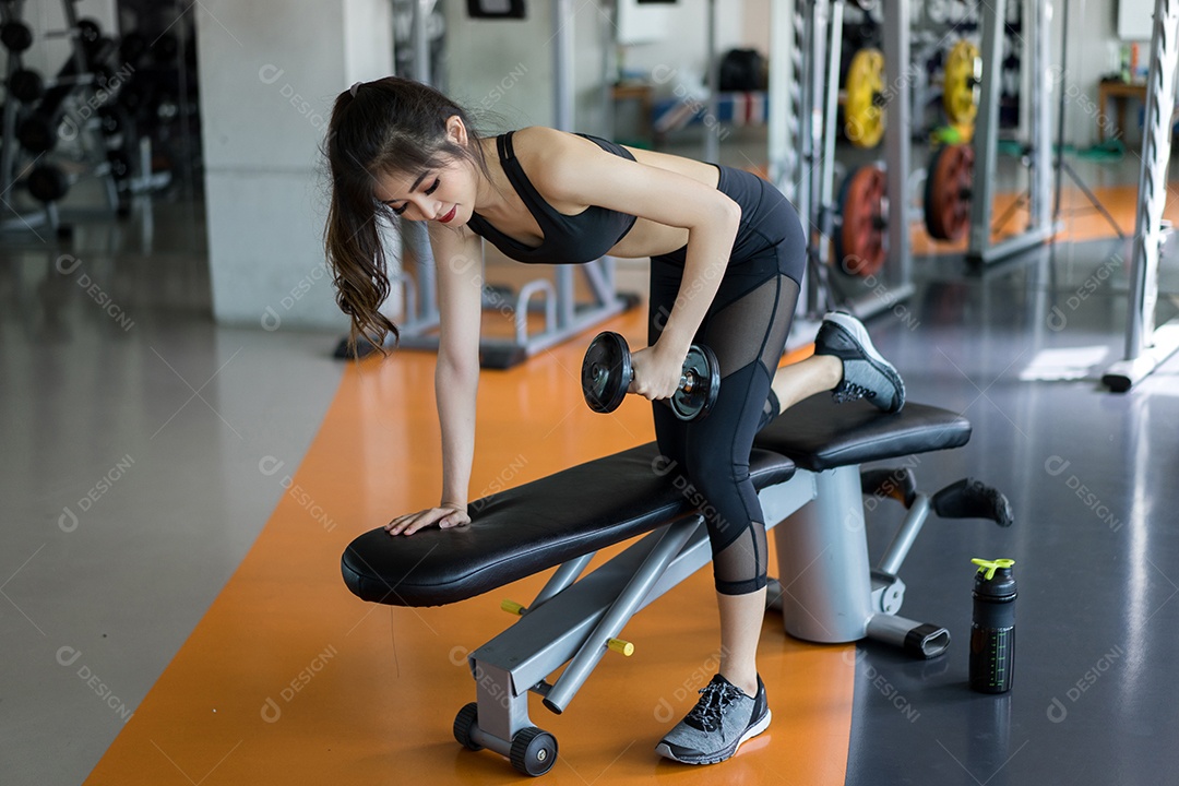 Mulher jovem asiática segurando halteres em um braço para exercício de treino muscular