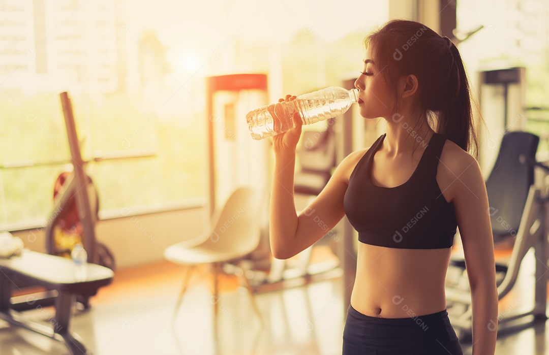 Mulher asiática bebendo água com garrafa após exercício de treino