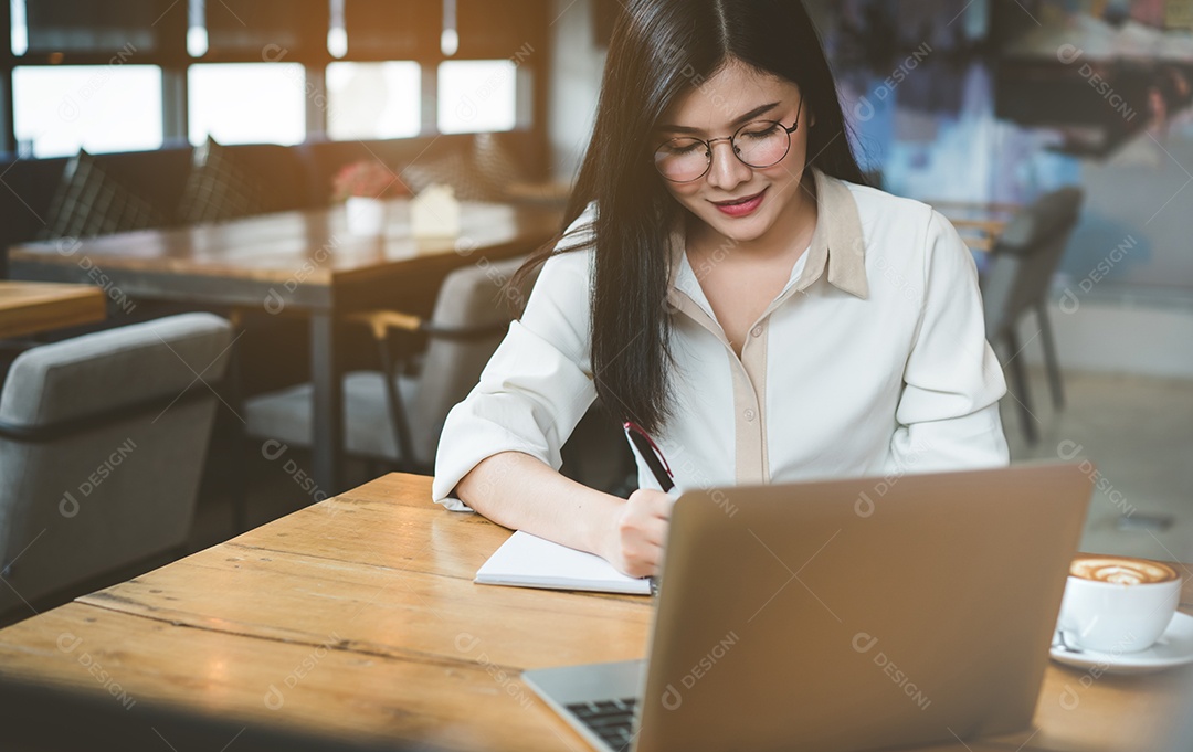 Mulher asiática freelancer trabalhando e escrevendo nota com computador portátil digital