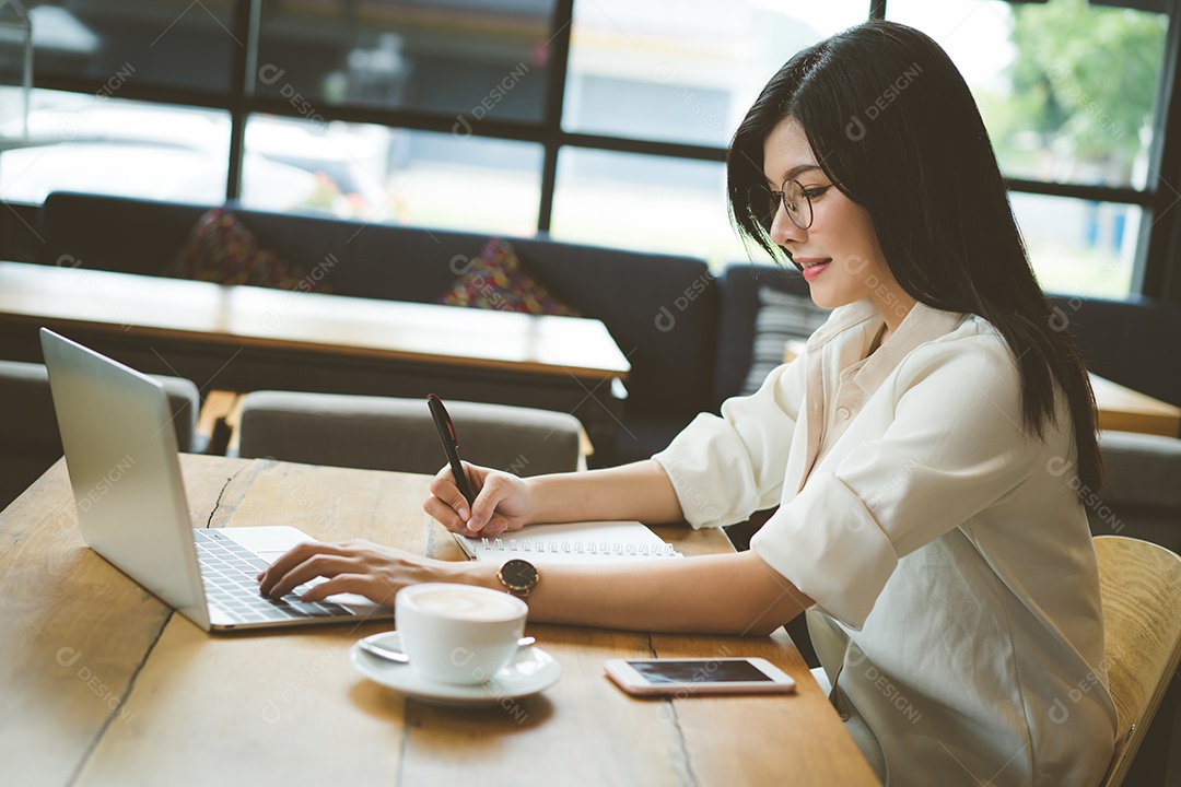 Mulher asiática freelancer trabalhando e escrevendo nota com computador portátil digital