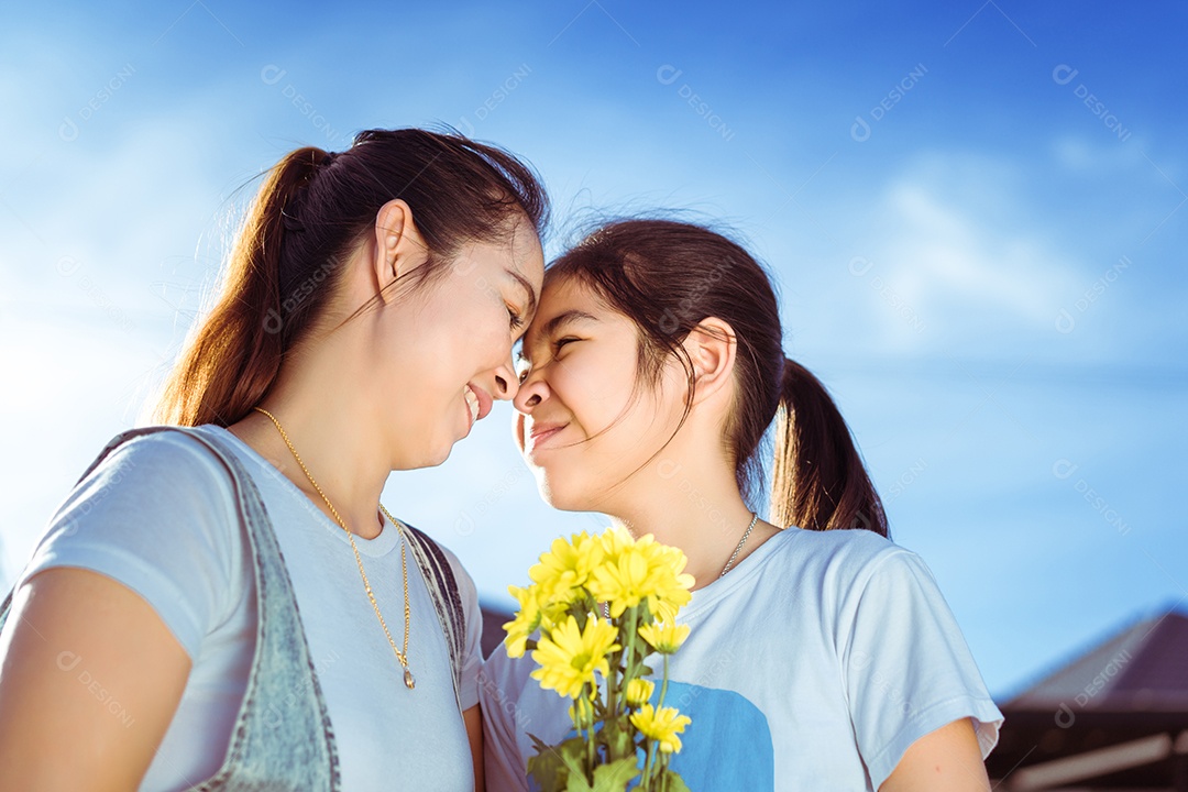 Mãe de família beijando filha com abraços na luz do sol