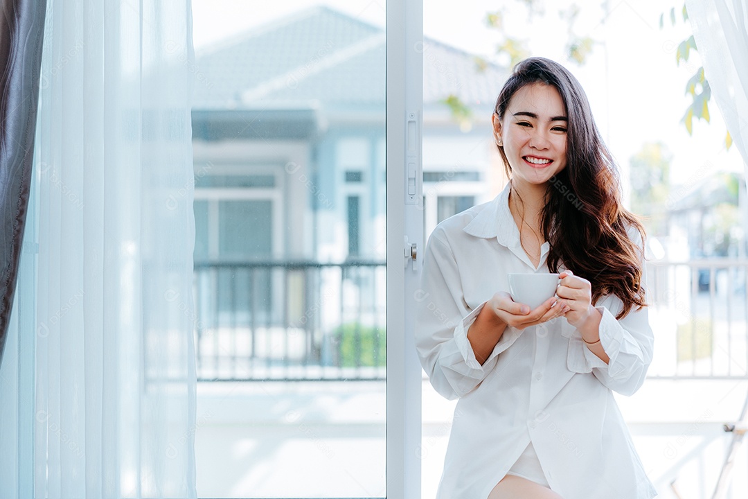 Mulher asiática acorda de manhã e abre a janela depois de acordar