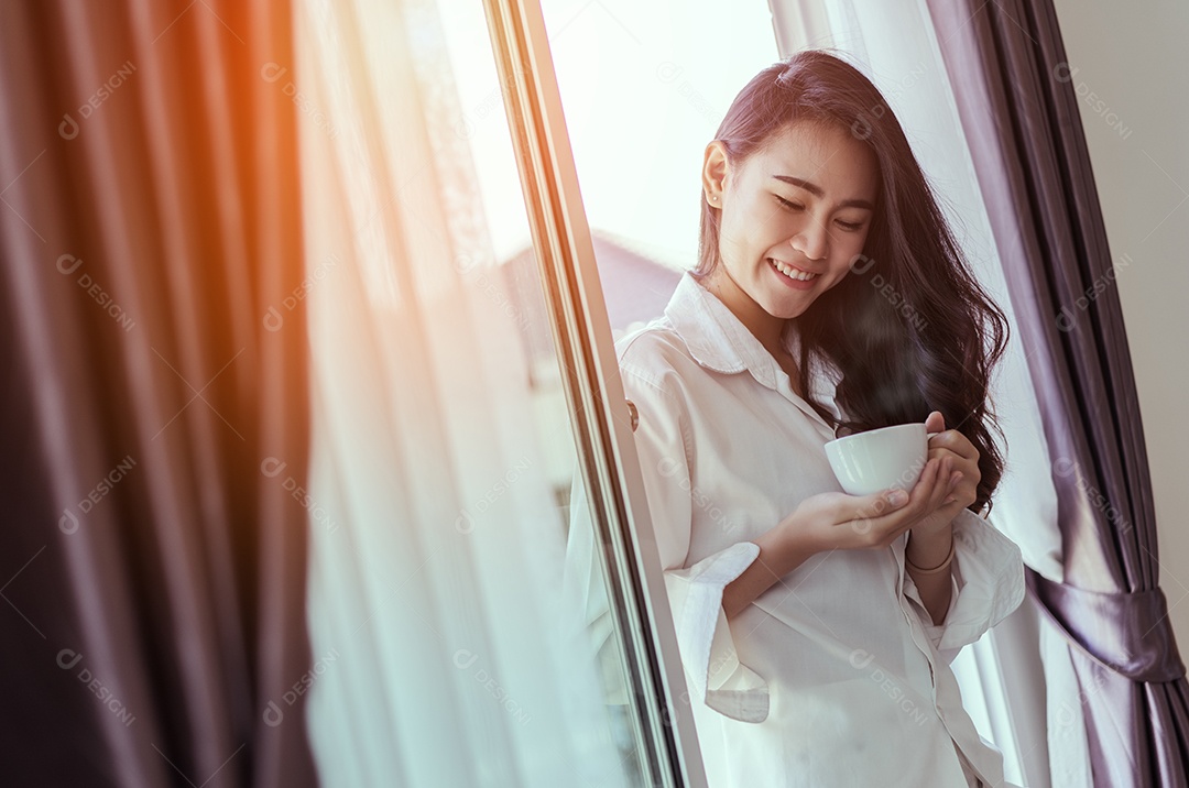Mulher asiática acorda de manhã e abre a janela depois de acordar