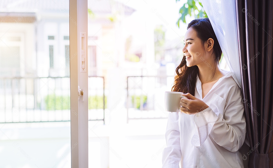 Mulher asiática tomando café da manhã na janela do quarto