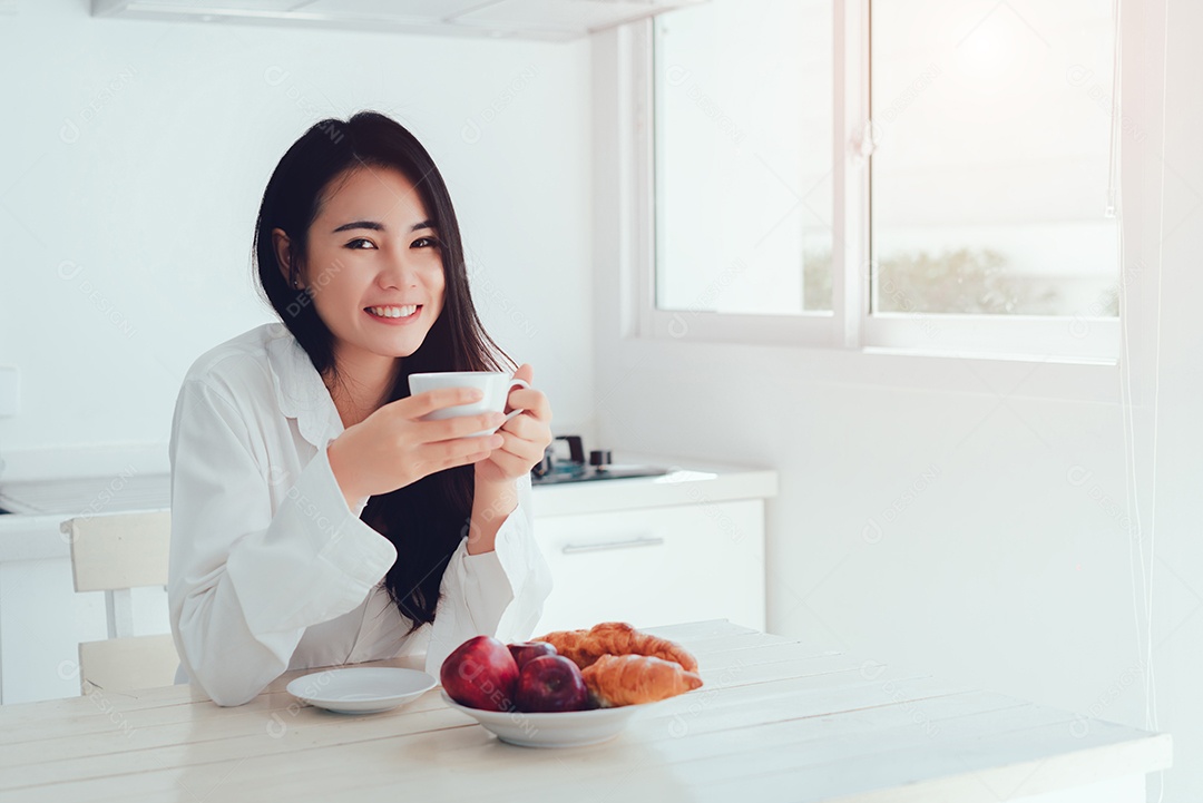 Mulher asiática tomando café pela manhã e comendo pão, maçã, fruta, comida saudável