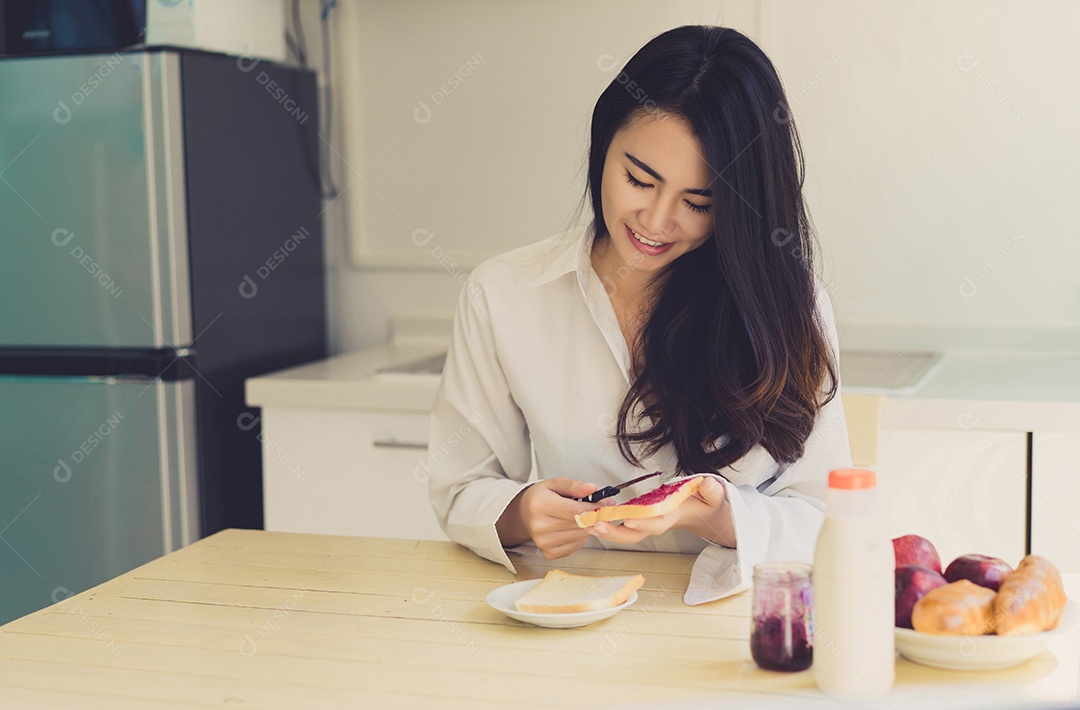 Mulher asiática fatia pão de geleia pela manhã e come frutas de maçã, café, comida saudável
