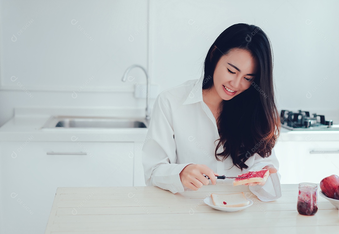 Mulher asiática fatia pão de geleia pela manhã e come frutas de maçã, café, comida saudável