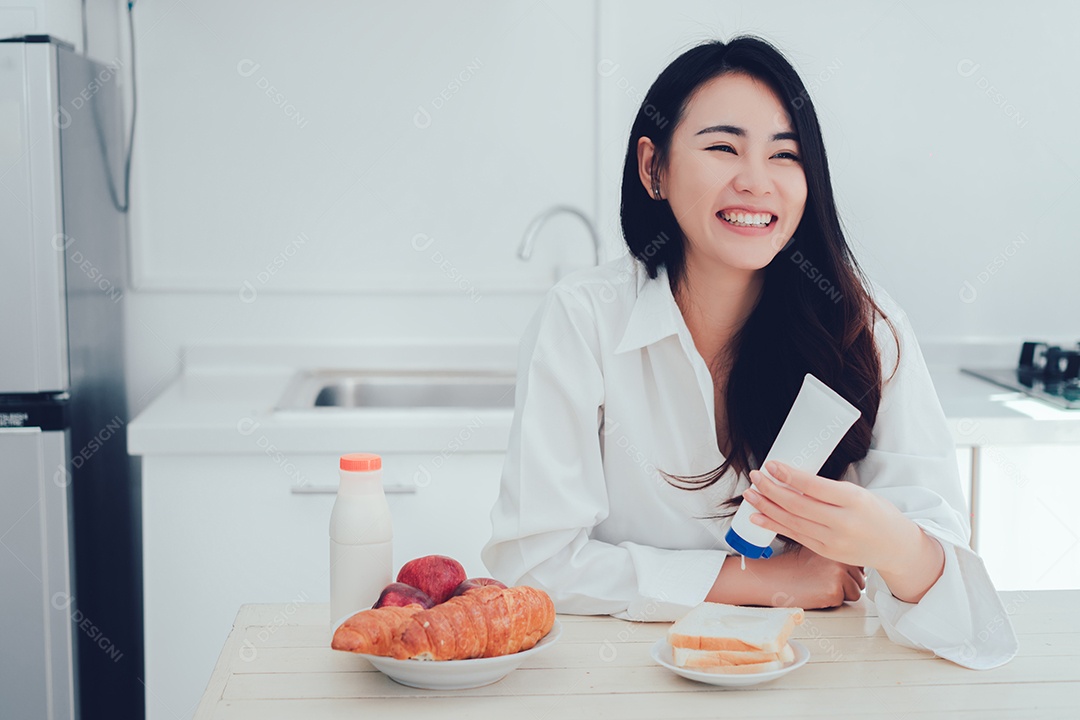 Mulher asiática fazendo pão com leite condensado adoçado, leite doce com especiarias pela manhã