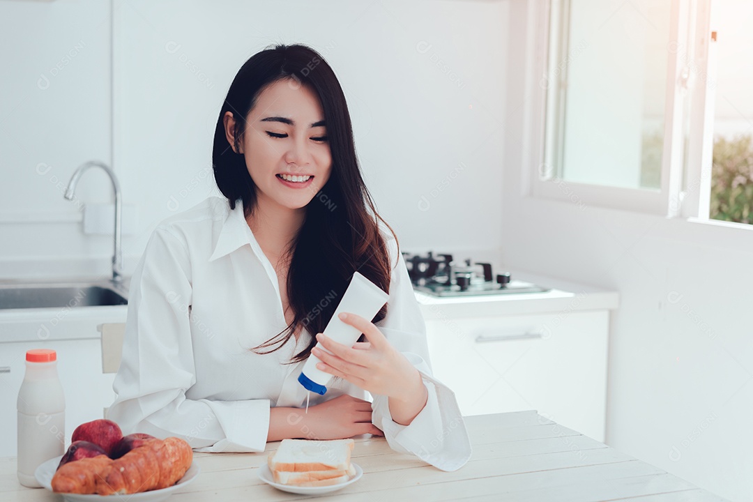 Mulher asiática fazendo pão com leite condensado adoçado, leite doce com especiarias pela manhã