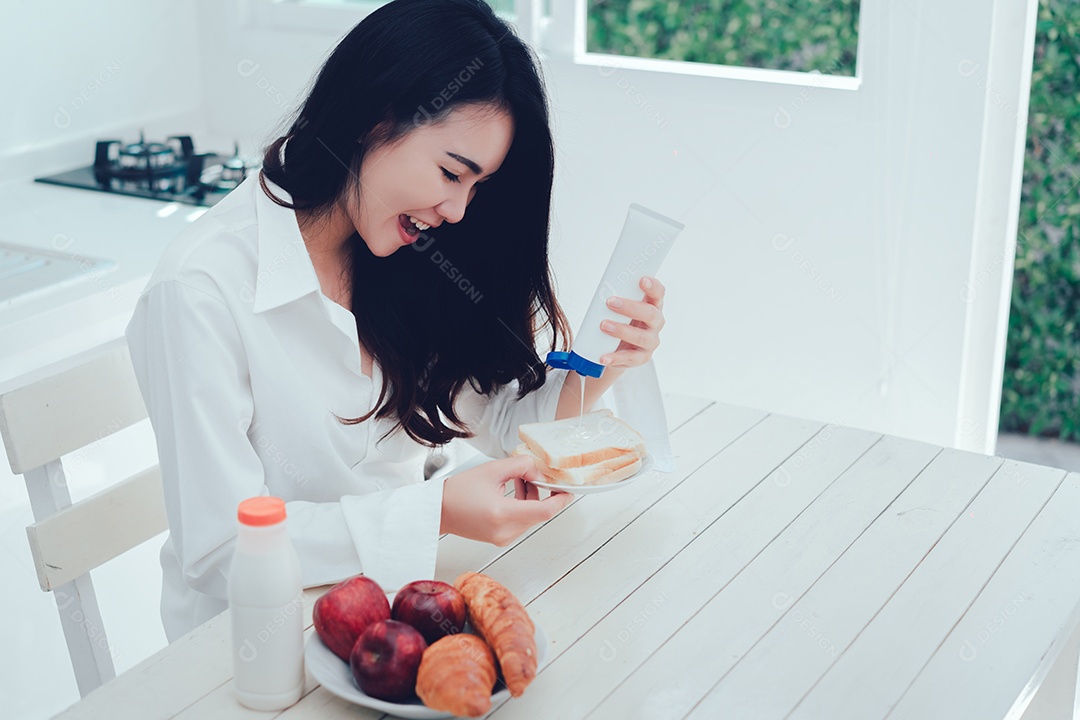 Mulher asiática fazendo pão com leite condensado adoçado, leite doce com especiarias pela manhã