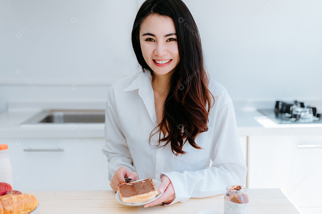 Mulher asiática fatia pão de geleia pela manhã e come frutas