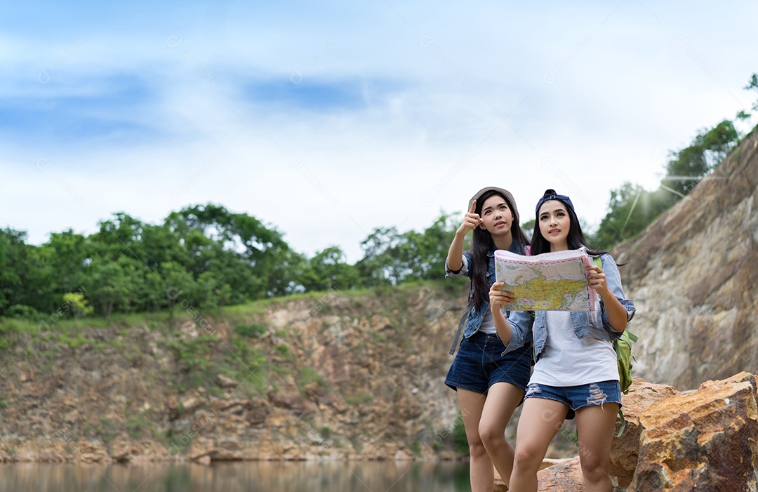 Menina asiática junto com a mochila em pé na rocha grande, mapas abertos, localização, viagem, aventura na montanha e no lago