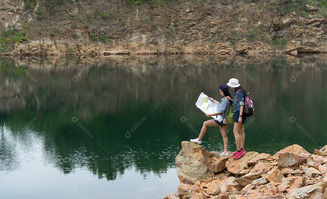Menina asiática junto com a mochila em pé na rocha grande, mapas abertos, localização, viagem, aventura na montanha e no lago