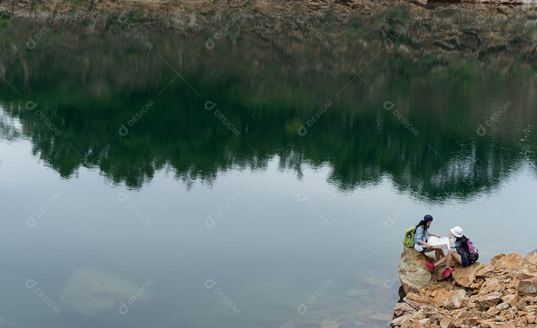 Menina asiática junto com a mochila em pé na rocha grande, mapas abertos, localização, viagem, aventura na montanha e no lago
