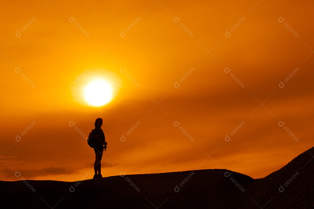 Menina asiática de mochila termina destinos na montanha olhando a silhueta do pôr do sol